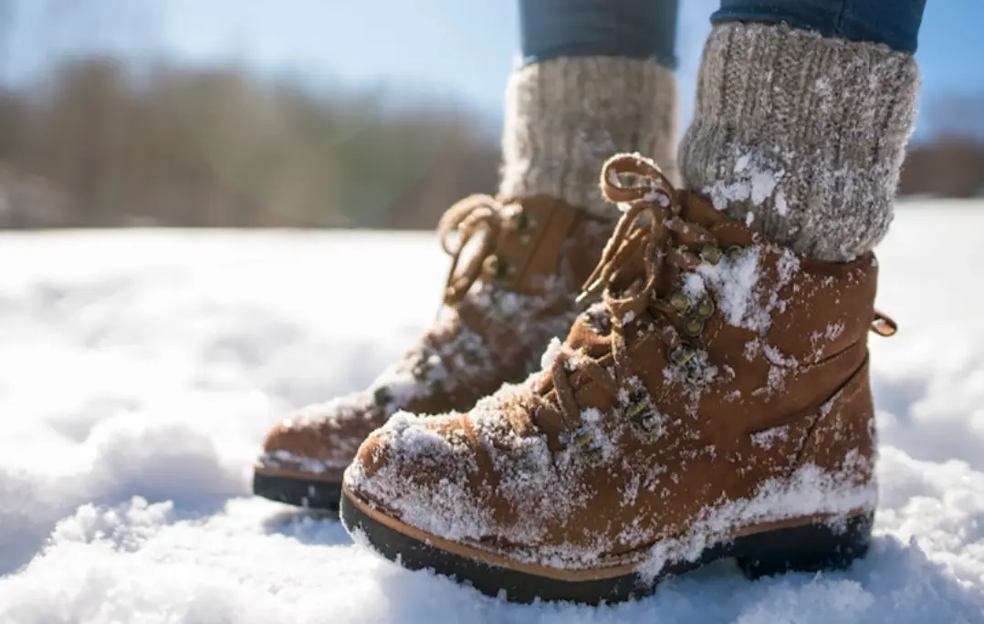 کفش‌های زمستانی چرمی پوشیده از برف، در حال پیاده‌روی روی زمین برفی